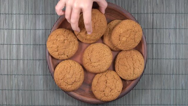 Plate full of oatmeal cookies being snatched up by five hungry children girl. Close up, top view, macro