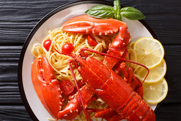 Italian recipe of spaghetti with boiled lobster, tomatoes, lemon and fresh herbs close-up. horizontal top view