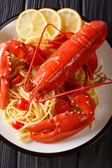 Italian recipe of spaghetti with boiled lobster, tomatoes, lemon and fresh herbs close-up. Vertical top view