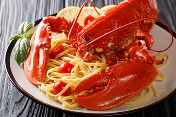 Luxury food recipe: spaghetti and boiled lobster, tomatoes, lemon and fresh herbs close-up on a black background. horizontal