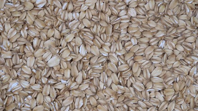 Dry oat flakes grains background, close up rotation loopable 4k top view. Food  background. Gastronomy concept, organic food. Macro rotation oat flakes