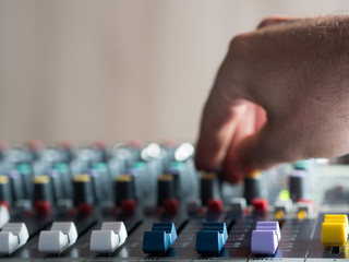 Man adjusting buttons on audio mixer