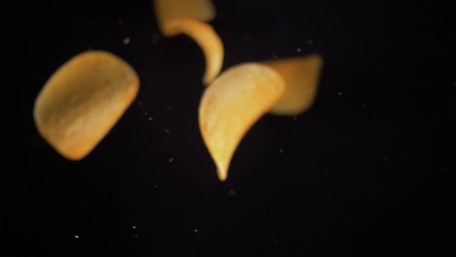 Potato chips flying up on black background. The view from the top. Pringles. Lays