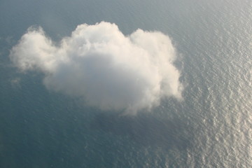 The view of the passenger from the window of the aircraft on a lone cloud, which is reflected on the water surface of the Black Sea.