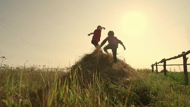 Two boys jumping on a haystack slow motion