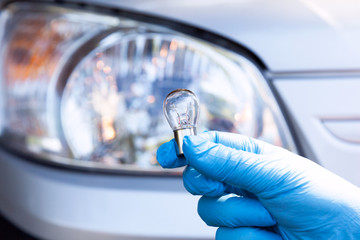 Close up of a light bulb with car headlight in the background