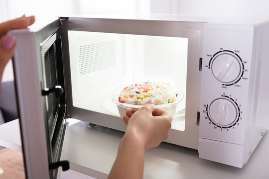 Woman Heating Food In Microwave Oven