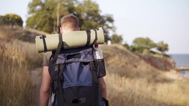 Adventure, travel, tourism, hike and people concept. Backside traking view of friends walking with backpacks by hills from back