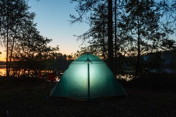 Night landscape with a tent in the mountains. The light from the lantern in a tent. Camping in the countryside. Crimea, Ukraine, Europe