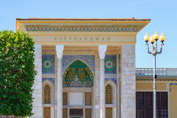 Naklejka premium Facade of pavilion Azerbaijan on Exhibition of Achievements of National Economy (VDNH) in Moscow closeup against green trees and blue sky on a sunny summer morning