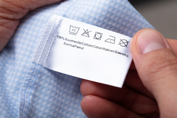 Man Holding Cloth Label Showing Washing Instructions