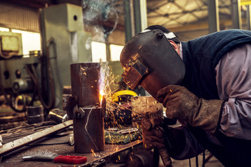 Fototapeta premium Close up of a male industry worker in protective uniform cutting metal pipe.