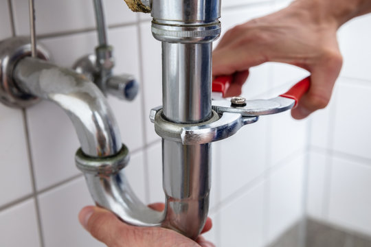 Plumber Repairing Sink With Adjustable Wrench