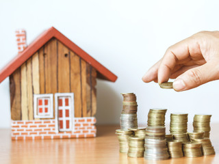 hand stacking coin and wooden house on desk, Property investment and house mortgage financial concept