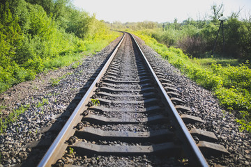 Rail tracks in the green field. Railway transport industry. Empty road on summer day. Travel lifestyle motivation photo.