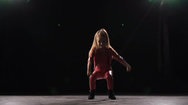 Little child does a handstand in the studio . Black background