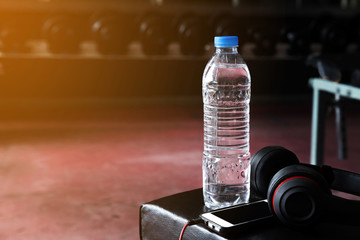 Water bottle and mobile phone and earphones in the gym.Fitness concept