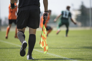 Legs of assistant of football referee with the flag 