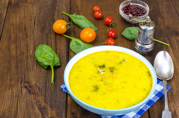 Creamy cream soup with spinach and tomatoes on wooden table