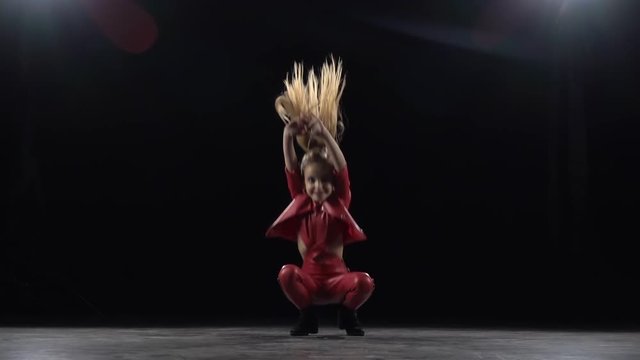 Child girl sit on the twine in the studio. Black background. Slow motion