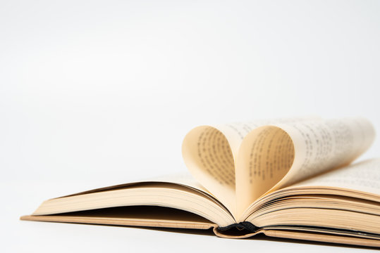 close up of opened book with heart shaped from two pages, isolated on white background.