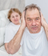 senior man plugged his ears, so as not to hear the scolding wife