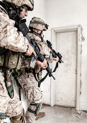 Marine assault team, counter-terrorism squad members, commando fighters in body armor, armed with service rifles, stalking through corridor to closed door, clearing rooms in abandoned city building