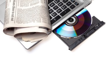Newspaper laying on a laptop with an open disc drive