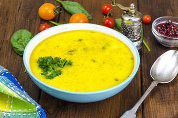 Creamy cream soup with spinach and tomatoes on wooden table