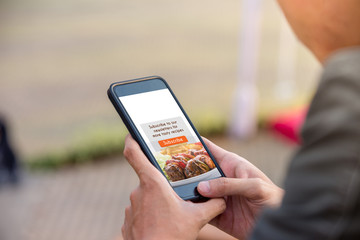 Food blog subscription concept. Man holding smartphone doing subscribe food blog on screen. - 219415927