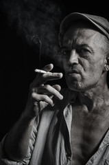 An elderly man in a cap and with a cigarette.