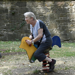 eine seniorin schaukelt auf einem kinderspielplatz