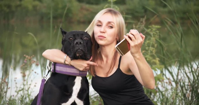 Attractive young woman is making a photo portrait with her dog on a smartphone. Concept: A dog is a man's best friend, love of animals.