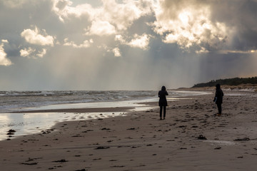 Fototapeta na wymiar Man och kvinna promenerar på en kall och blåsig strand