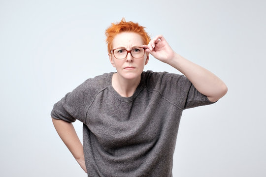 Surprised frustrated mature woman with red hair. She has problems with eyesight.