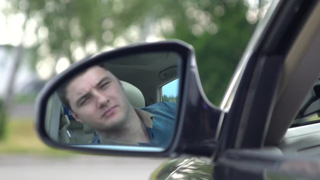 Young man driving a car checking behind him
