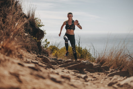 Fit woman running up the mountain trail