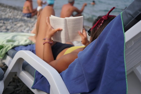 Relaxing with a good book at the beach. Selective focus
