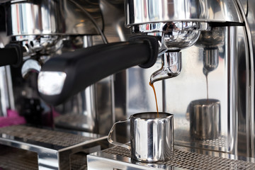 Espresso machine pouring coffee into a small metal jug.