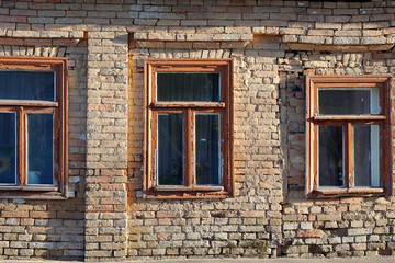Fototapeta na wymiar Facade of the old house in emergency condition of red brick with old wooden windows