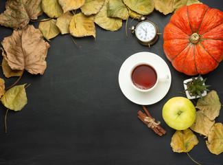 Tea with cinnamon and an alarm clock, a pumpkin and autumn foliage. flat lay season food items top view