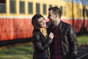 Fototapeta premium Young couple hugging on the background of a passing train.