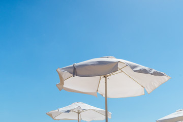 Fototapeta na wymiar white beach umbrellas on a background of blue summer sky