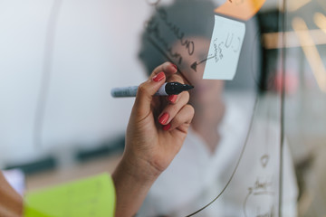 Woman writing on transparent board