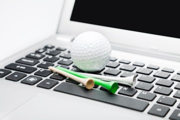 golf ball and some golf tees on a laptop computer
