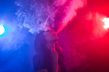 Young woman smoking vape or e-cigarette in neon light