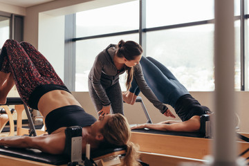 Pilates trainer instructing women at the gym