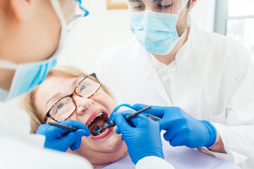 Zahnarzt während Behandlung von älterer Patientin 