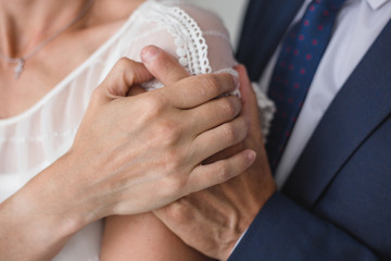 Closeup view of hands of bride and groom. Horizontal color image.