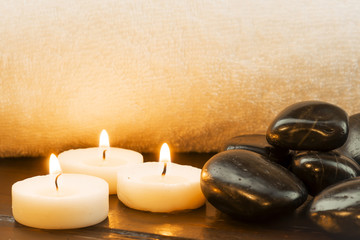 Obraz na płótnie Canvas Dark stones and candles on a white towel background